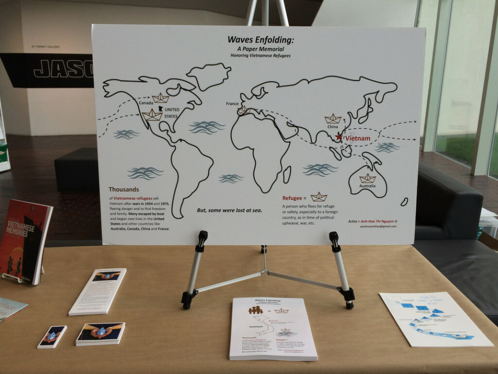 Papers are displayed on a table, including a large world map depicting routes of Vietnamese refugees.