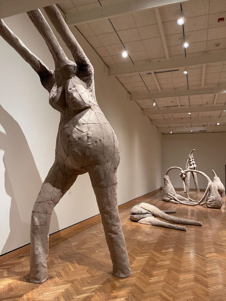 Gray felt sculpture with long legs reaches up