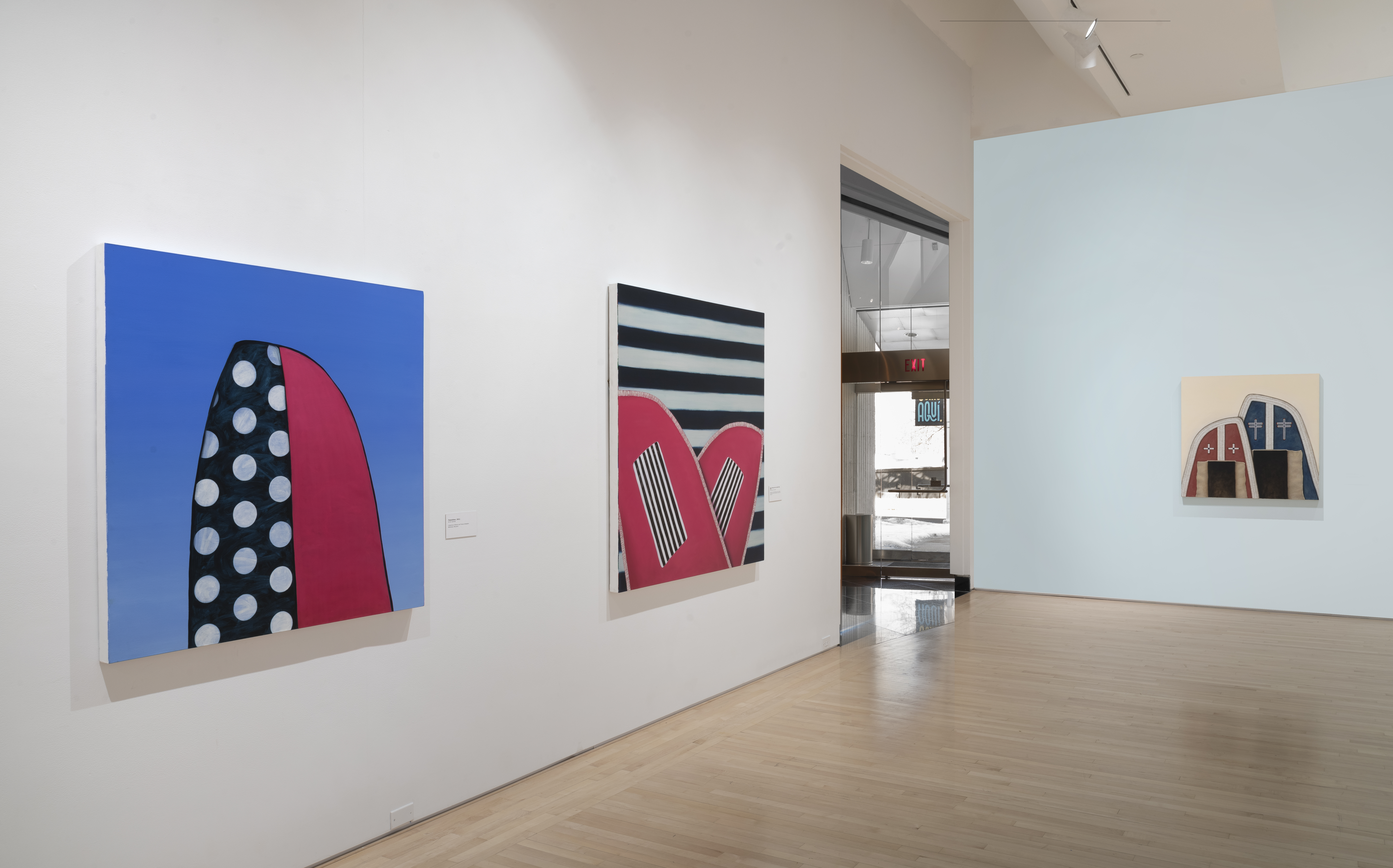 Abstract paintings in white-walled gallery.
