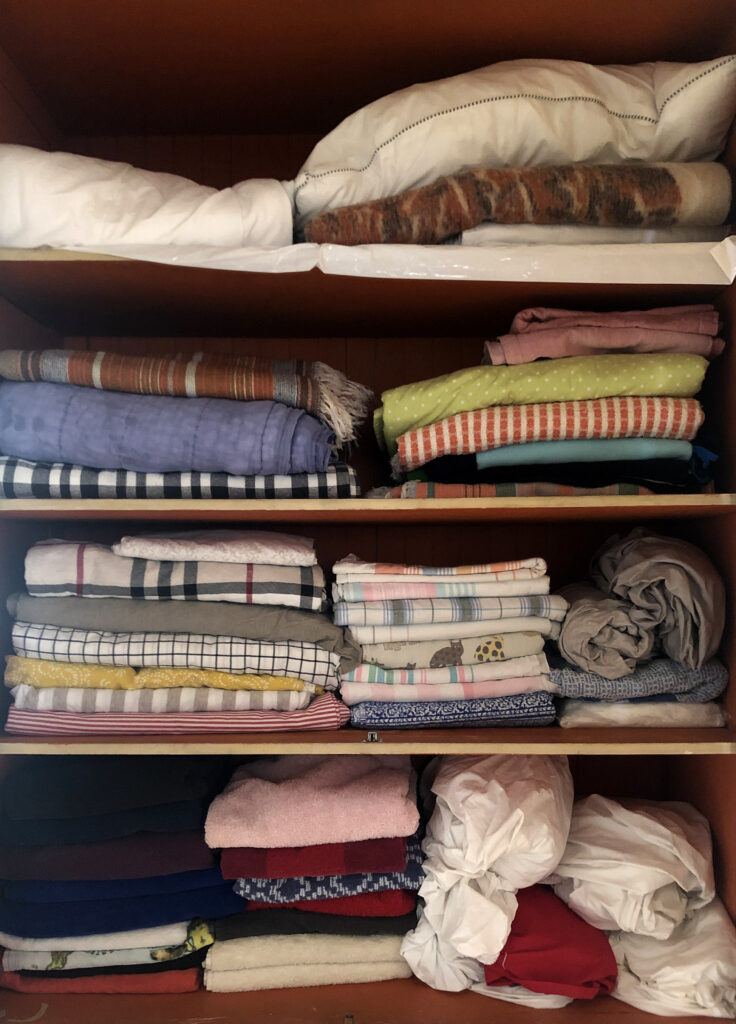 Stacks of folded multicolored textiles arranges on shelves.