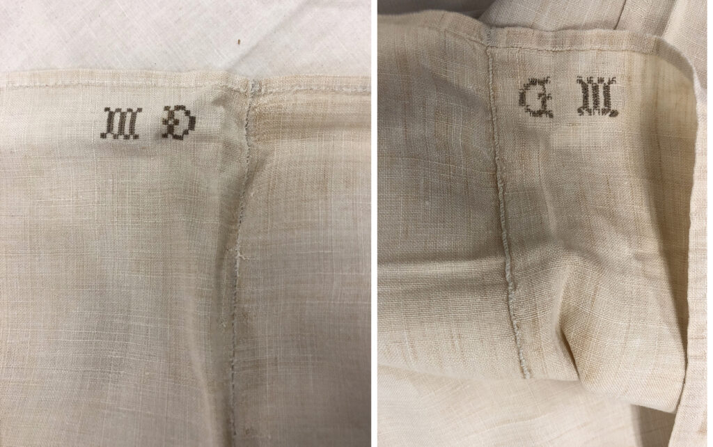 Off-white vintage textile with "MD" and "GM" embroidered in brown thread.