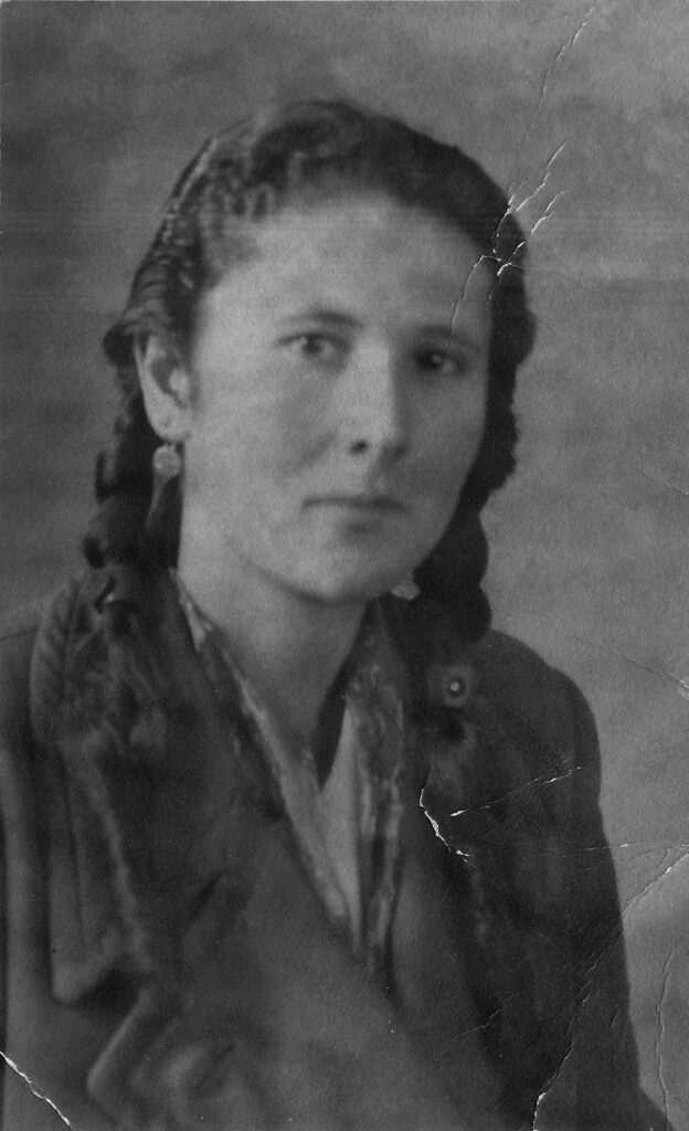 Black and white portrait of person with light skin, long dark braids, earrings, collared shirt and coat.