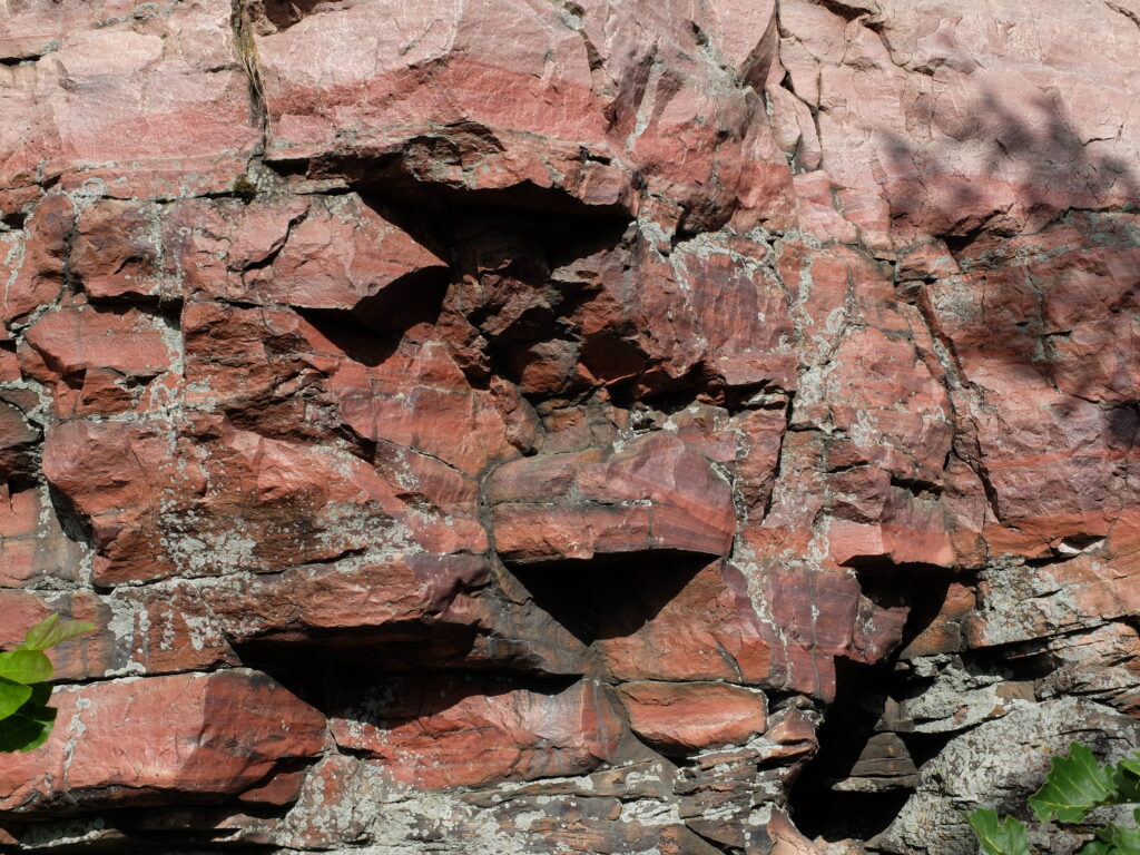 Rust-colored rock face with lighter and darker stripes.