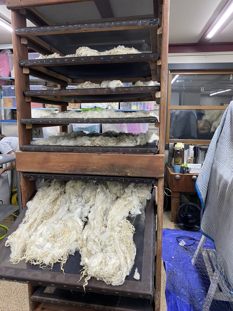 Wool spills out of tall wooden drying rack.
