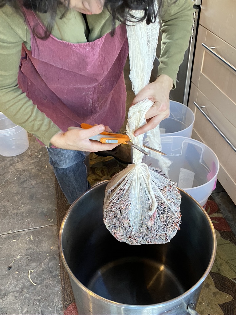 Person trims end of bundle wrapped in white mesh fabric with a pair of orange scissors.