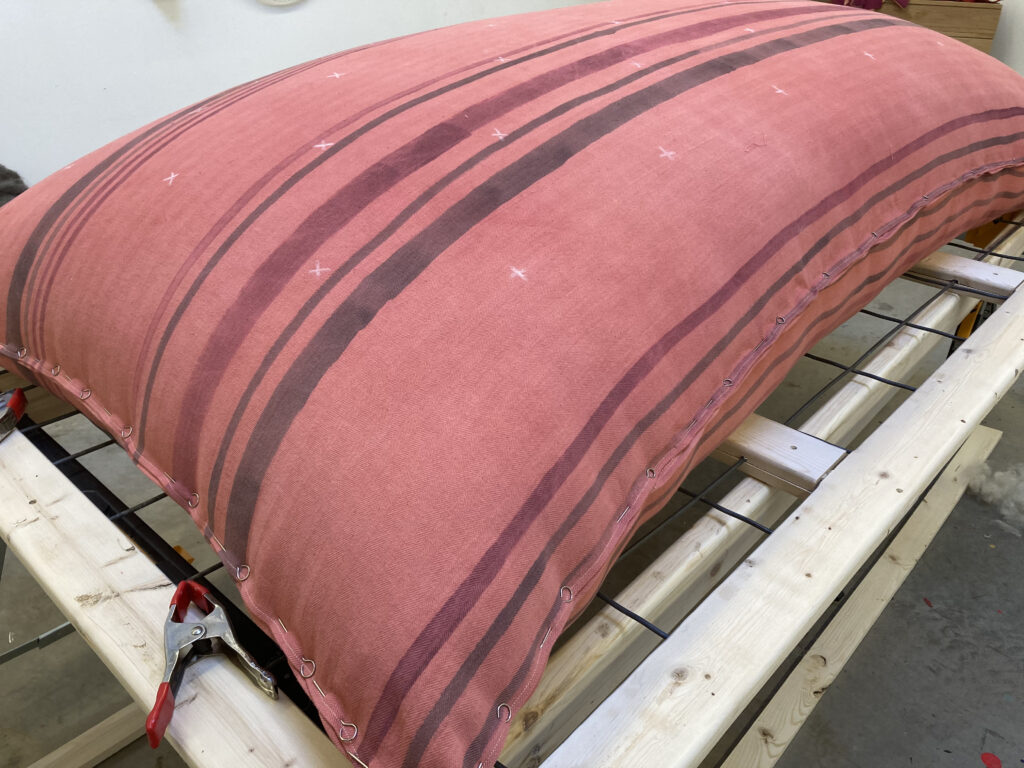 Striped red fabric mattress with no tufting.