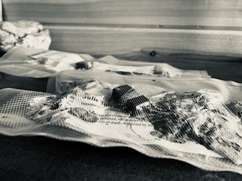 Black and white photo of herbs, paper, charcoal wrapped in plastic.
