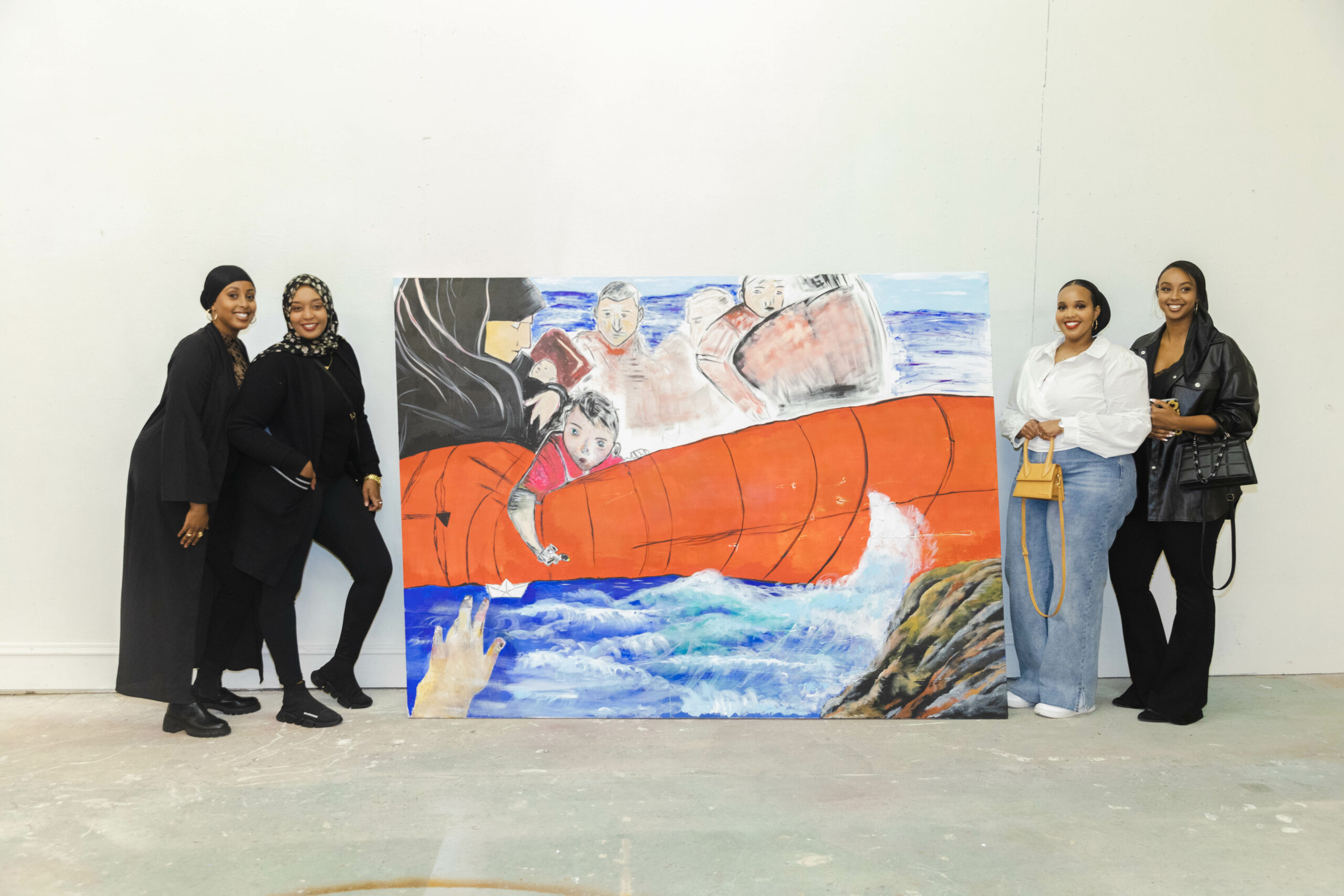 Four people stand on either side of large painting with orange life raft in blue water.