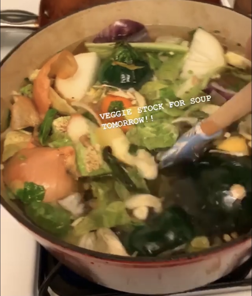 Large pot of soup with vegetable scraps, with text overlaid: VEGGIE STOCK FOR SOUP TOMORROW!