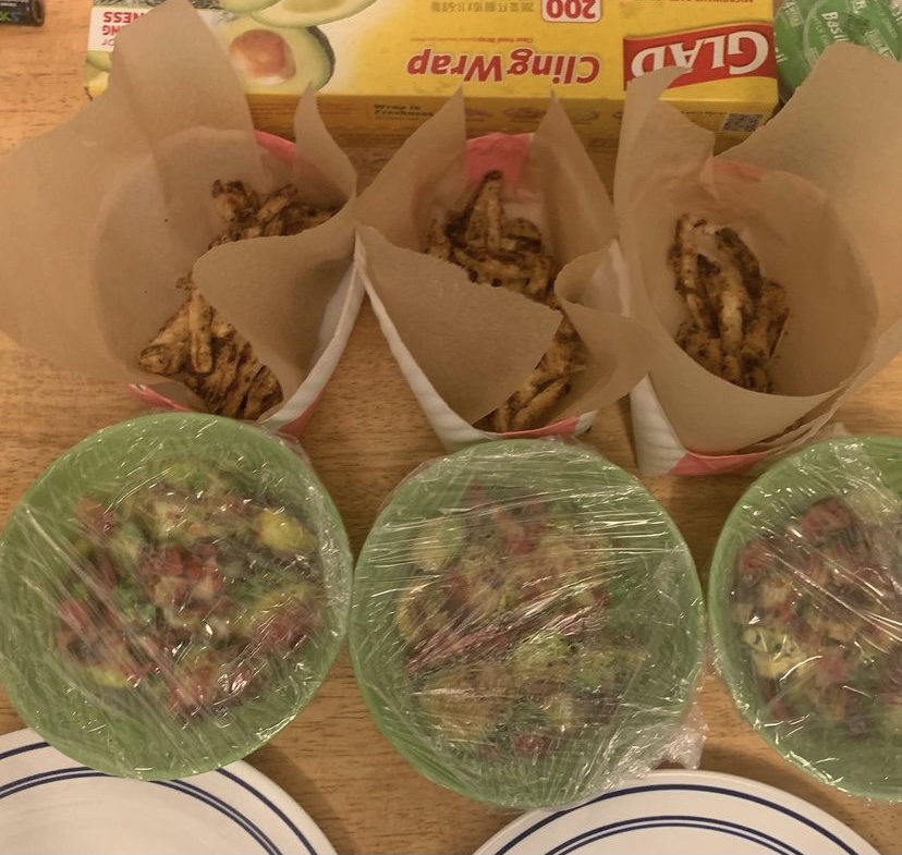 Many bowls of food packaged with cling wrap and parchment paper.