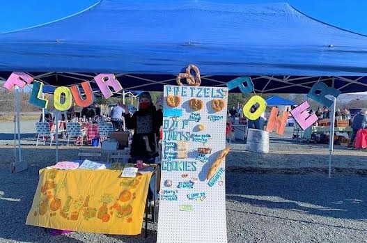 Booth with baked goods, large menu, blue awning, and large multicolored letters reading FLOUR POWER.