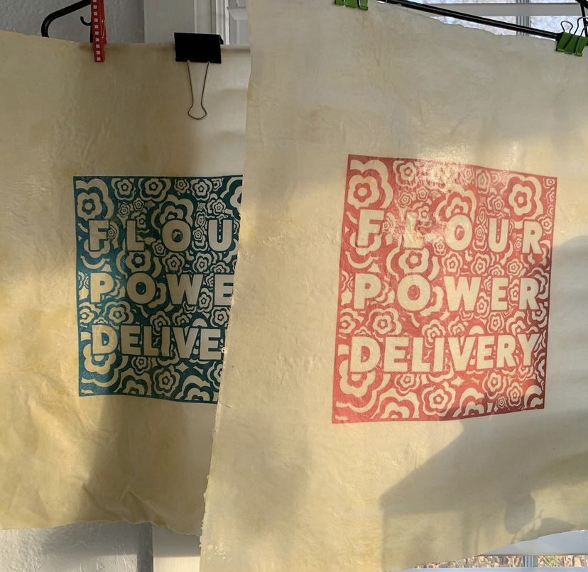 Beeswax wrappers with blue and red designs reading FLOUR POWER DELIVERY.