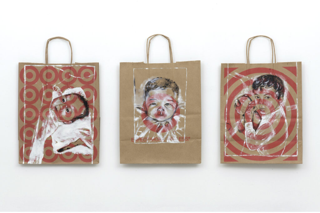 Three portraits of infants painted on brown shopping bags with red Target logos.