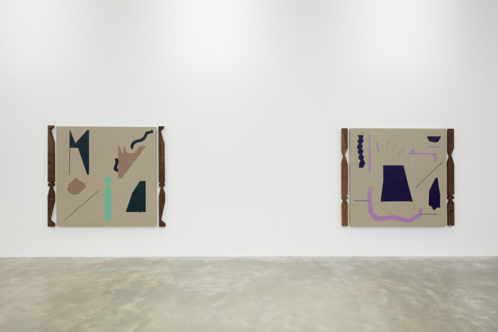 Two paintings with multicolored abstract shapes and beige background hang on white wall with tan floor.