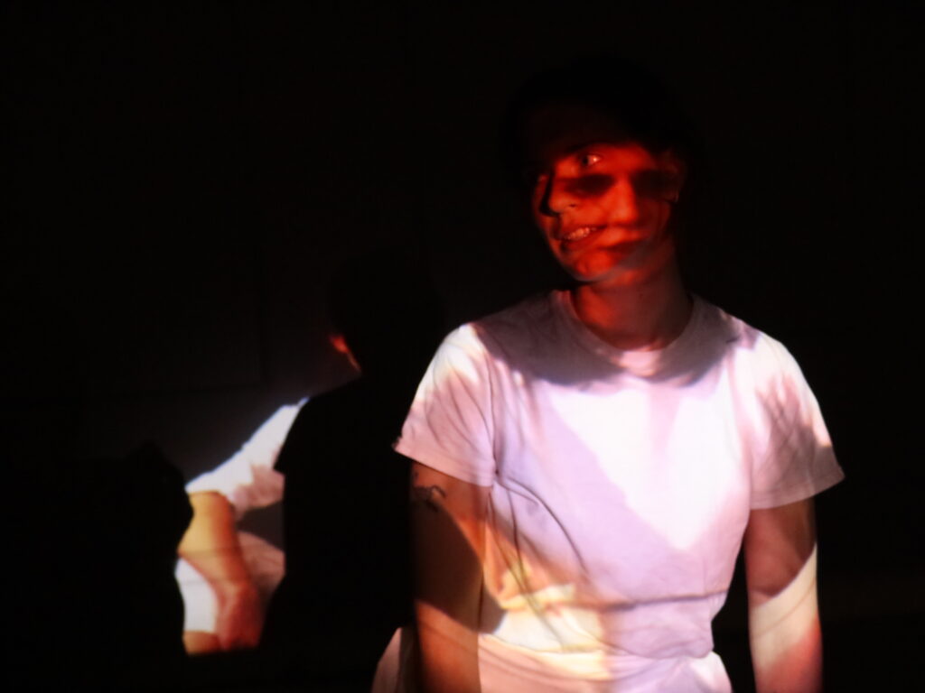 Person wearing white t-shirt looks to the side, while an image of their face looking forward is projected onto them.