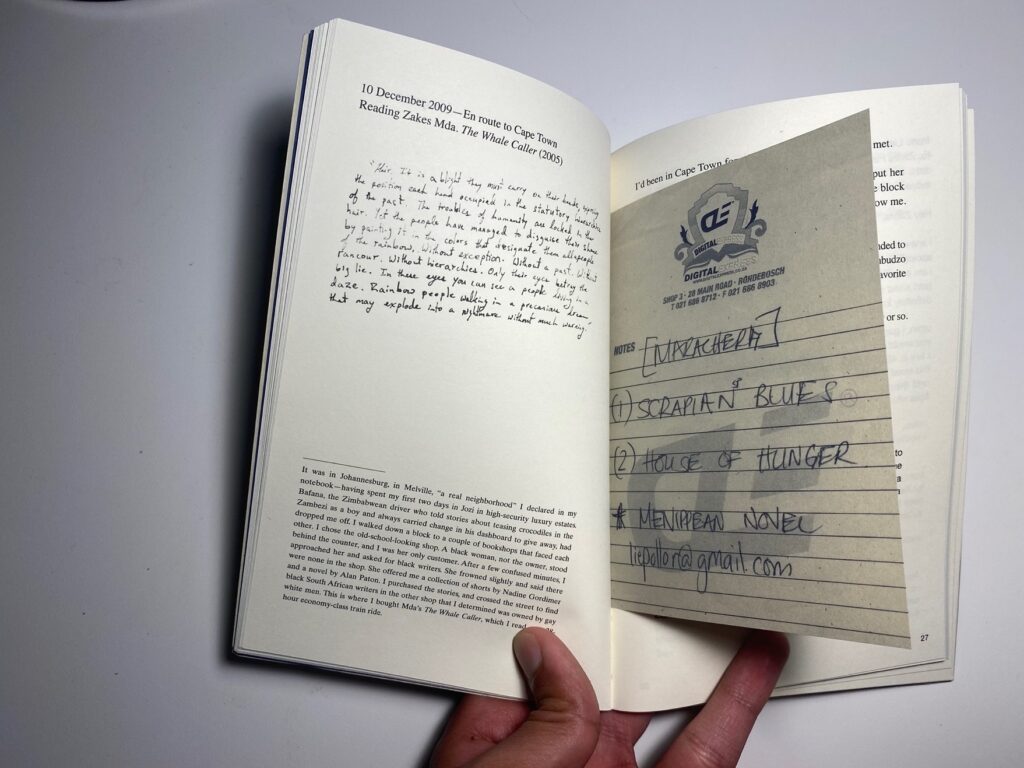 Hand holds open book with handwritten notecard between pages.