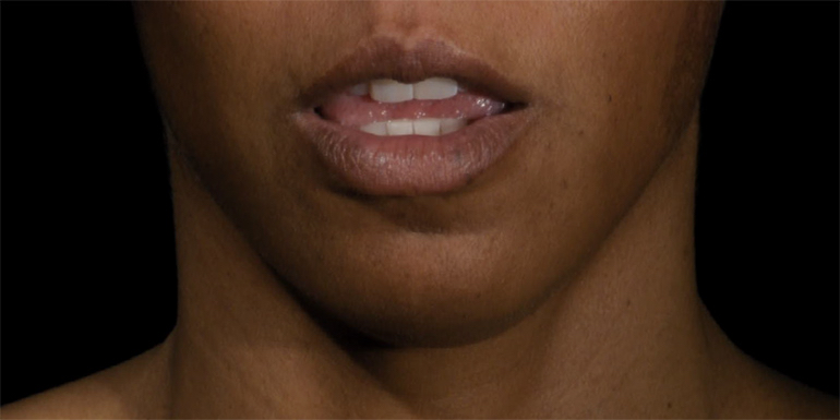 Person with dark skin and slightly open mouth, photo cropped between their top lip and their throat.