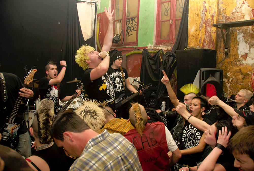 Punk band with crowd. Singer with microphone reaches in the air.