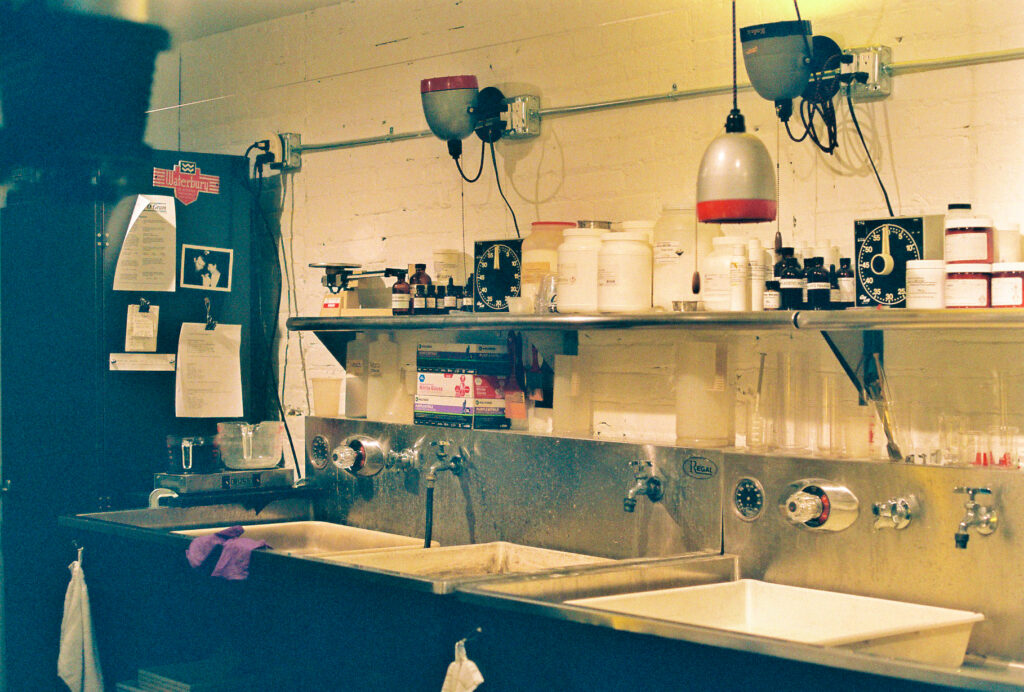 Darkroom with stainless steel sinks and shelves of equipment.