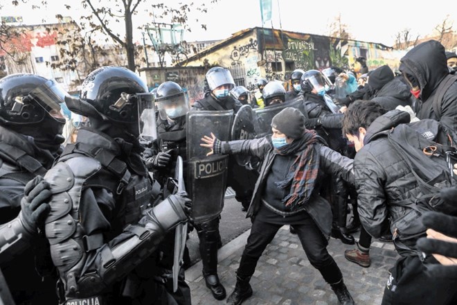 Protesters wearing black clash with police in riot gear.