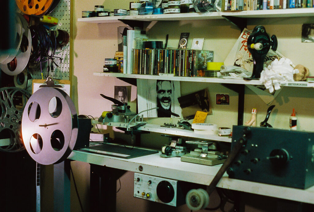 Desk and shelves with many film reels, CD cases, photos and memorabilia.