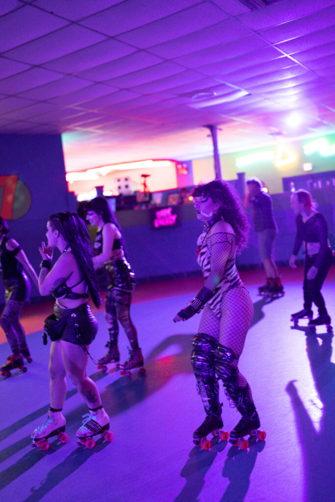 Roller skaters on rink with purple light.
