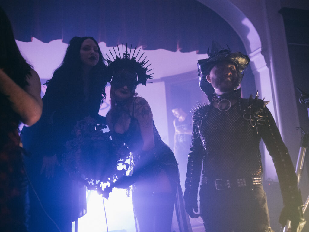 Silhouette of three people in front of purple light.