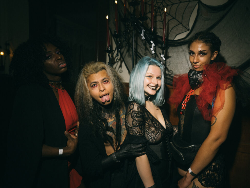 Four people in crowd with dyed hair and makeup wearing lace and tulle.