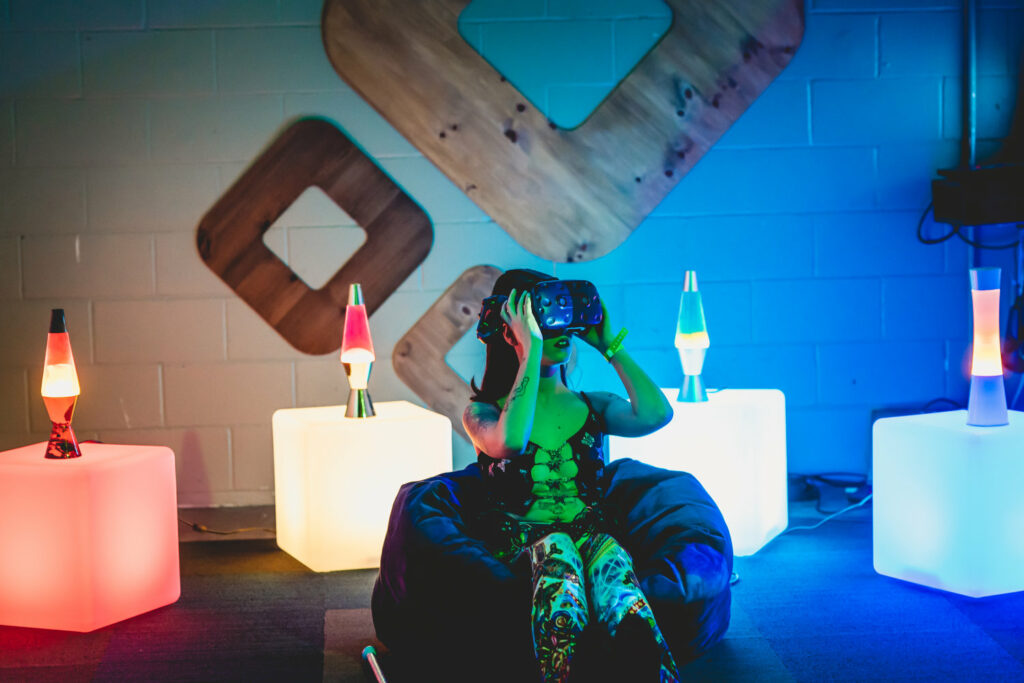 Person sits in beanbag chair wearing VR headset, with many lava lamps in background.