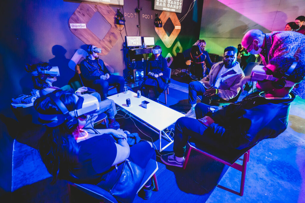 People gathered around a table with neon light and artworks in background.