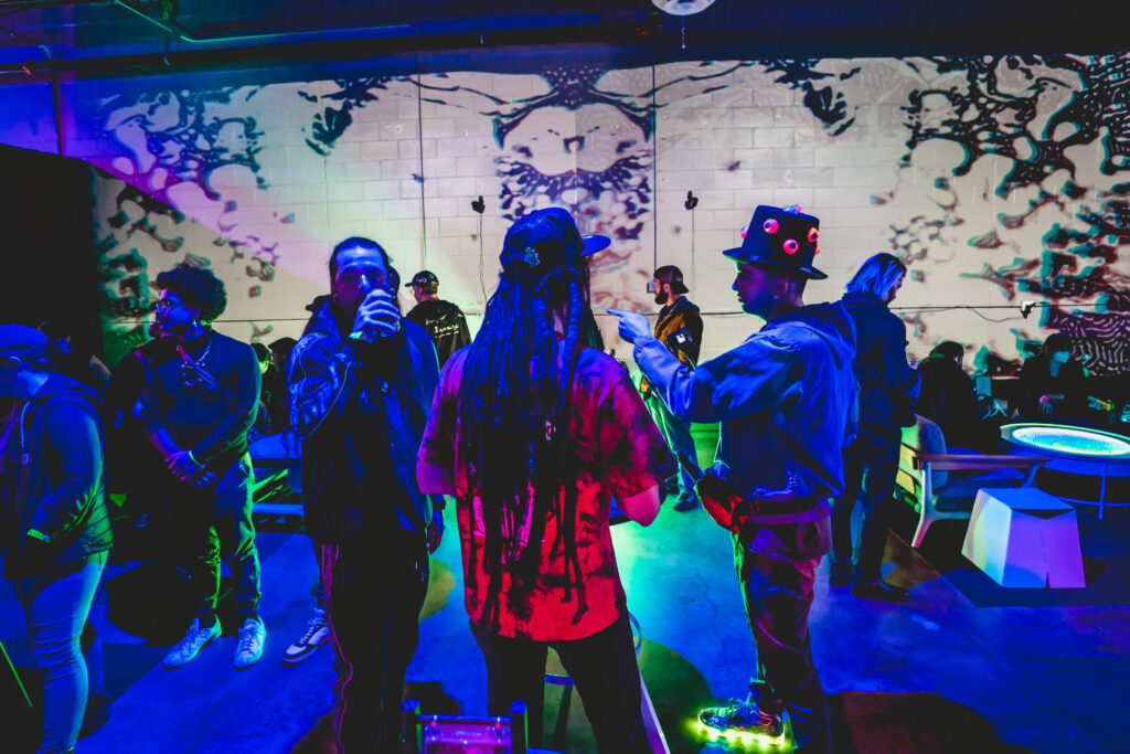 People gathered in a gallery with neon light.