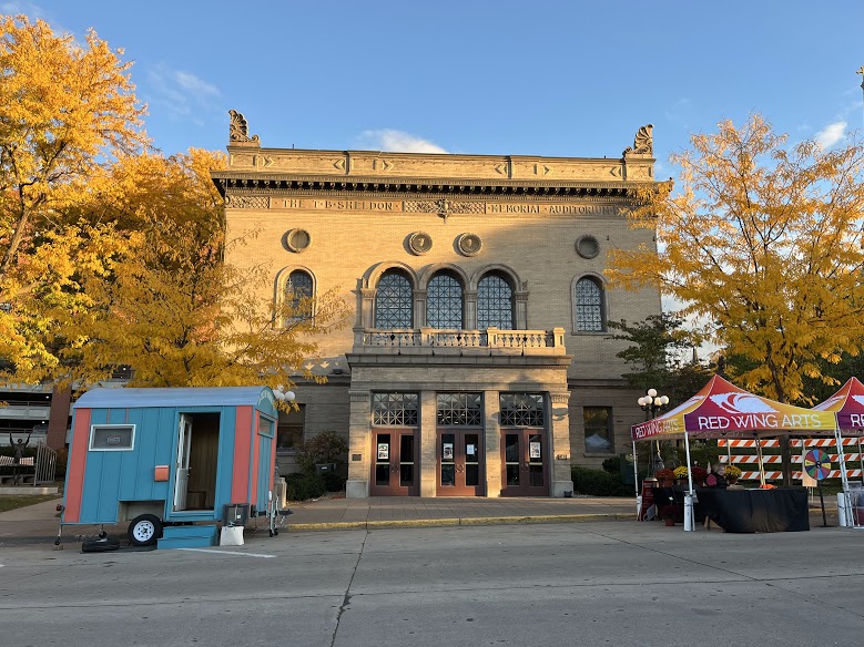 Turquoise and pink trailer on street in front of stone building in fall