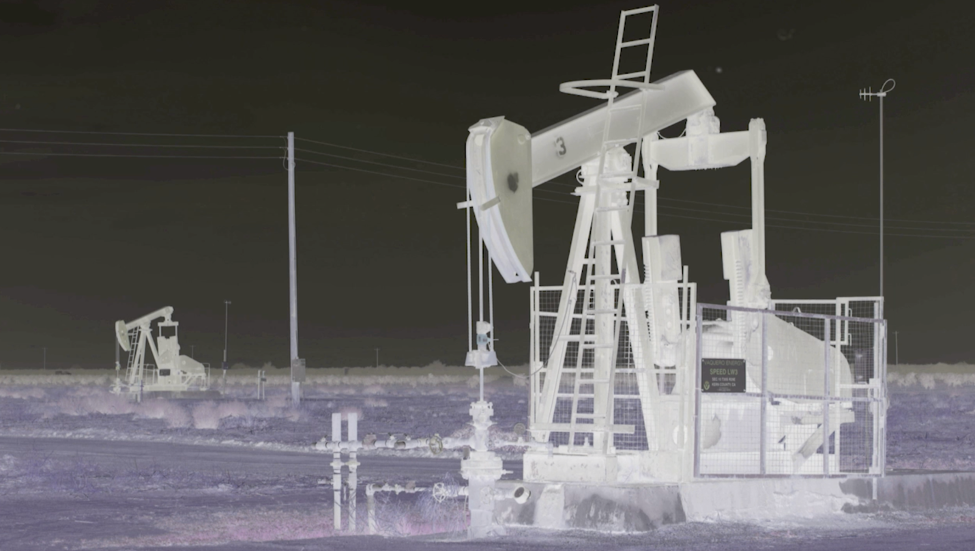 Two oil rigs, color-manipulated to be white, with lavender ground and dark sky.