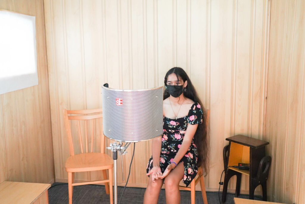 Young woman in wood-paneled room with sound recording equipment