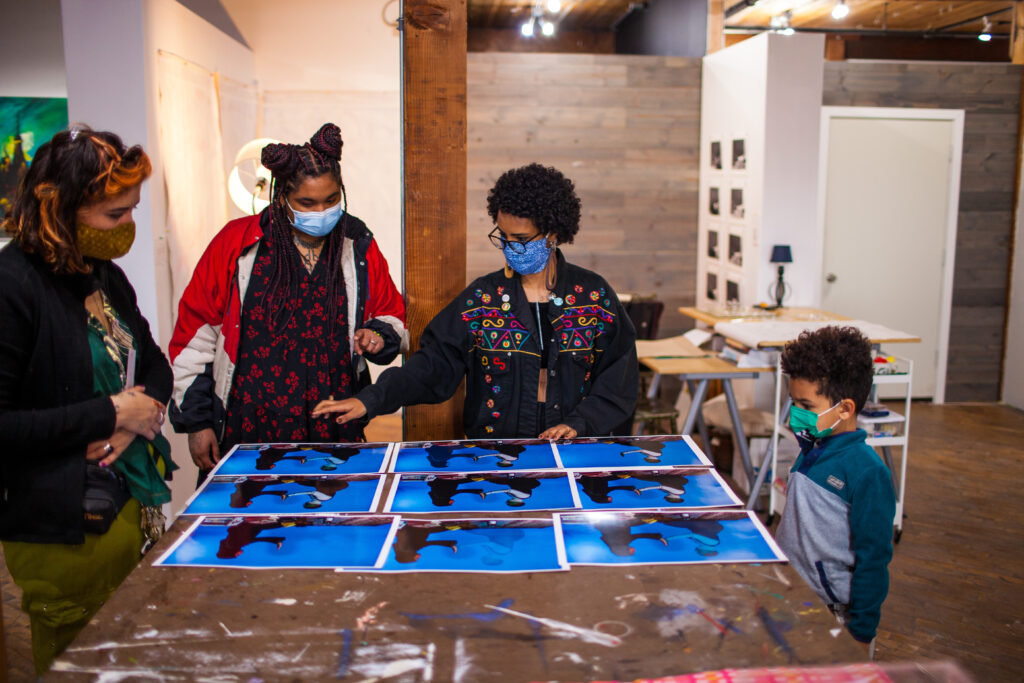 Masked people gathered around a studio table looking at a set of images