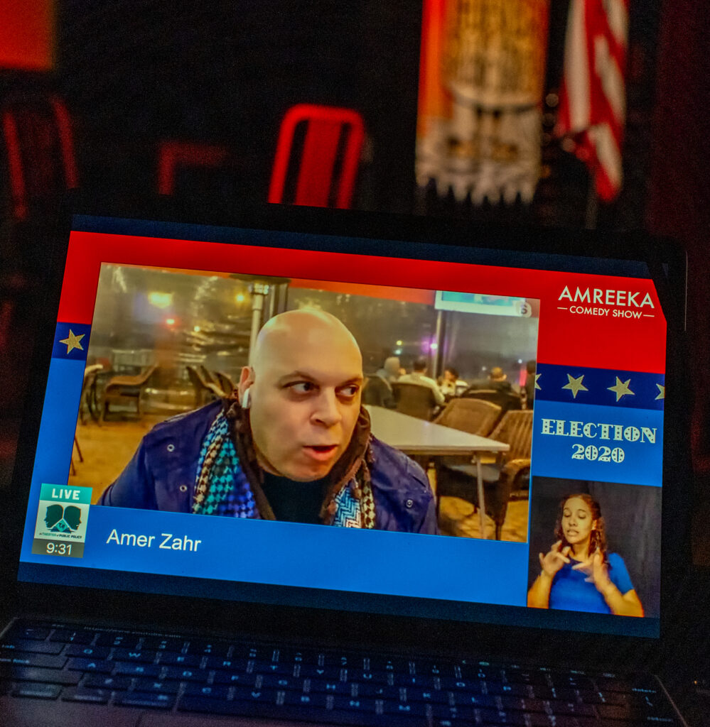 Laptop screen showing a person talking, an ASL interpreter, and text reading "Election 2020".