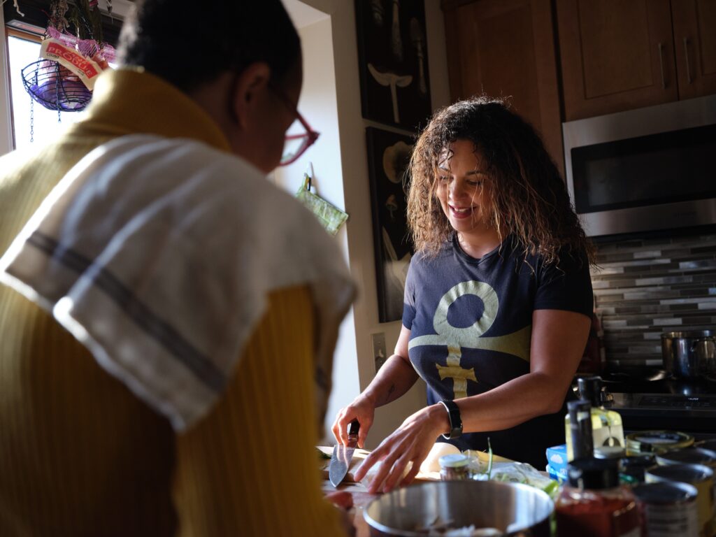 Two people stand over kitchen island, with bowls between them.