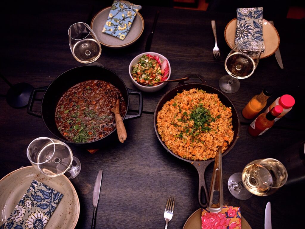 Table set with four place settings, cast iron pans of beans and rice, and bowl of salsa.