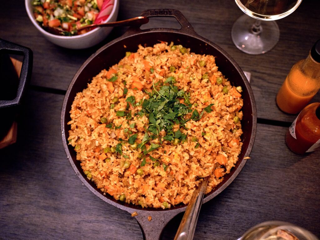 Cast iron pan of rice with wooden spoon and cilantro on top.