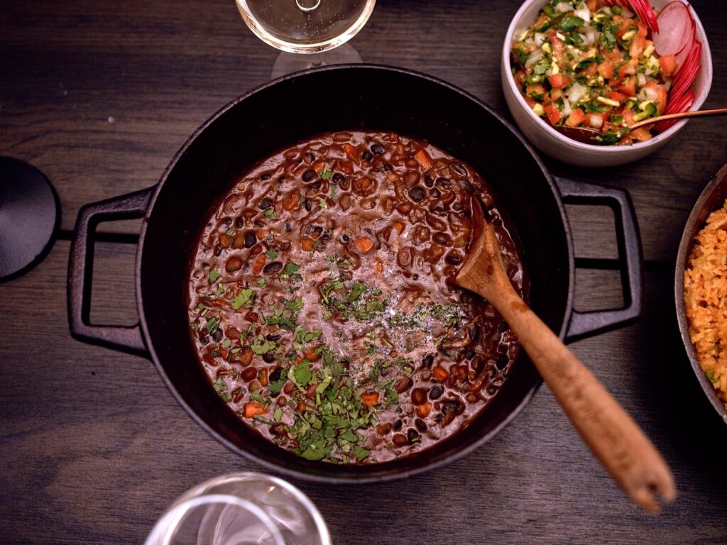 Cast iron pan of beans with wooden spoon.