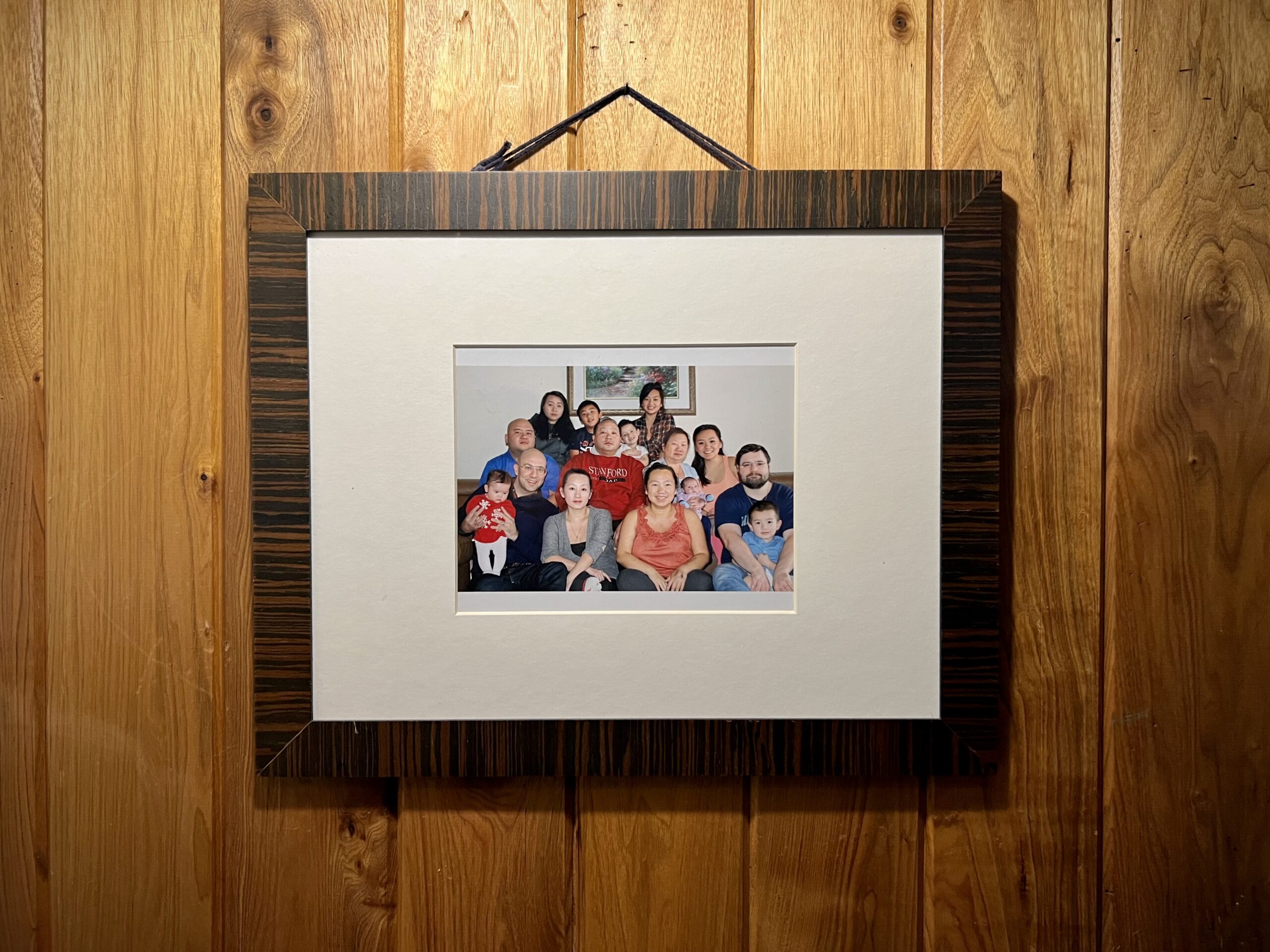 Group photo in dark wood frame hangs on wood paneled wall.