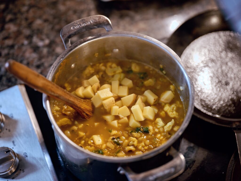 Pot of food on stove with wooden spoon.