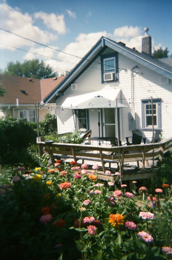 White house with back deck and garden with zinnias.