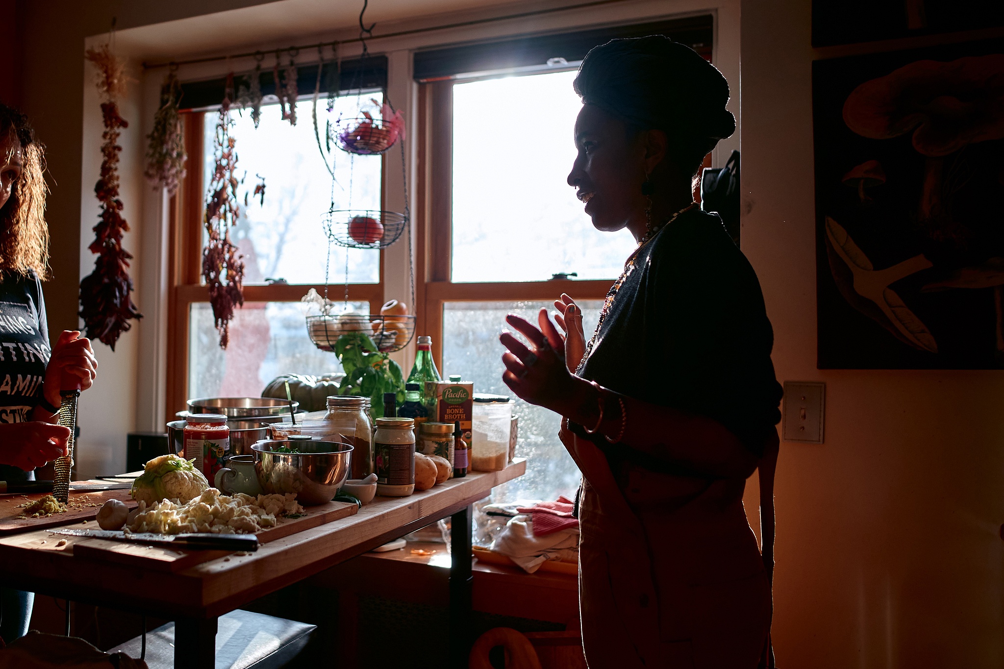 Silhouette of person wearing headwrap in front of kitchen island, light streaming in window.