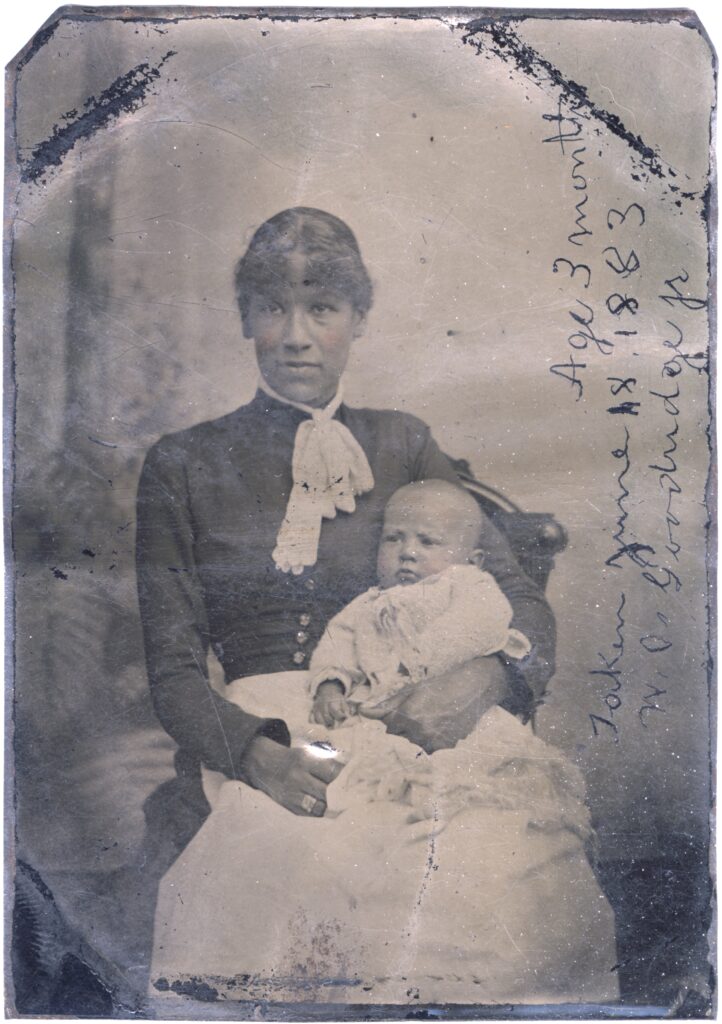 Old faded portrait of woman with an infant in her lap.