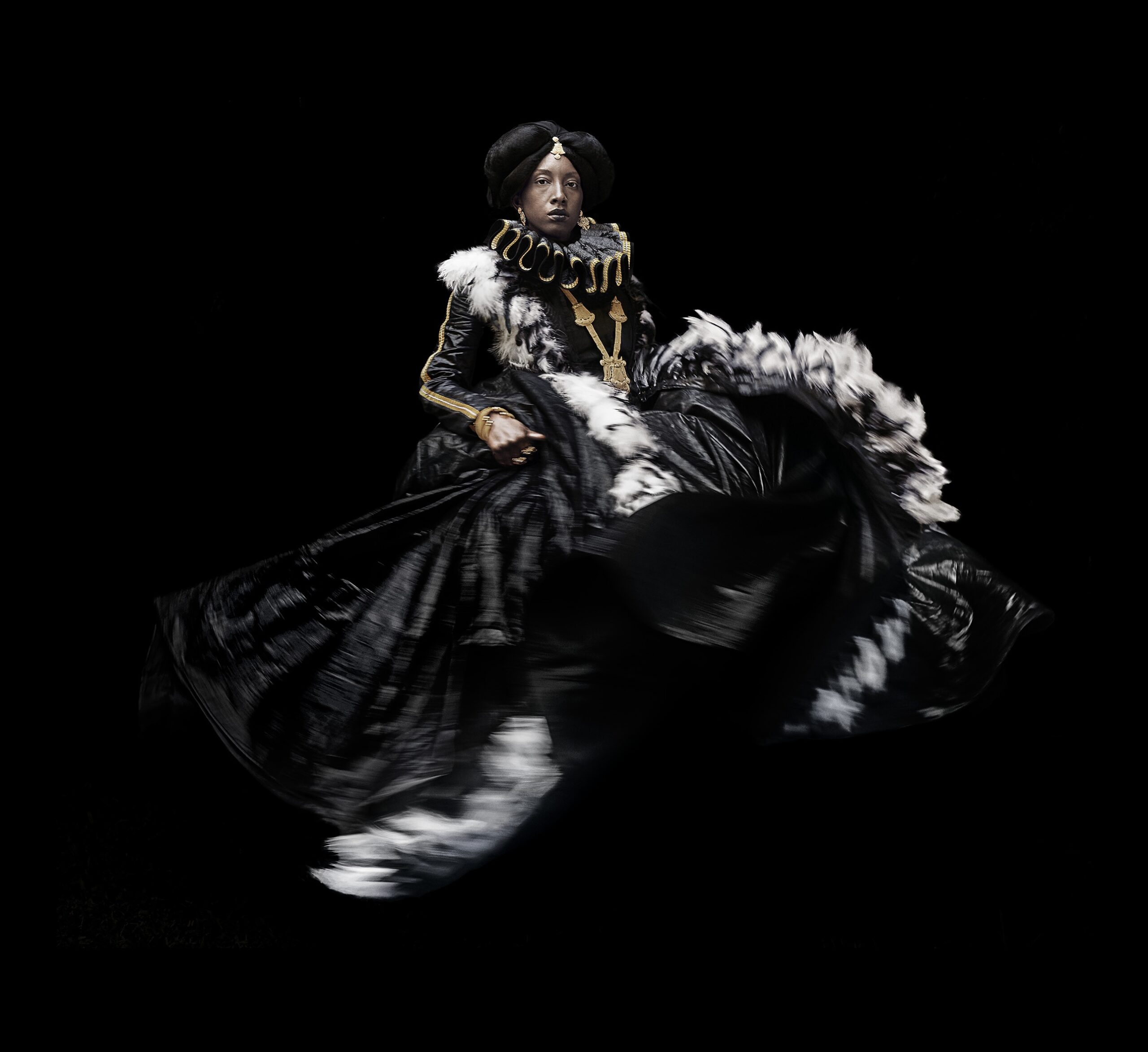 Portrait of dark skinned person in elaborate victorian-like dress moving feather-trim skirt.