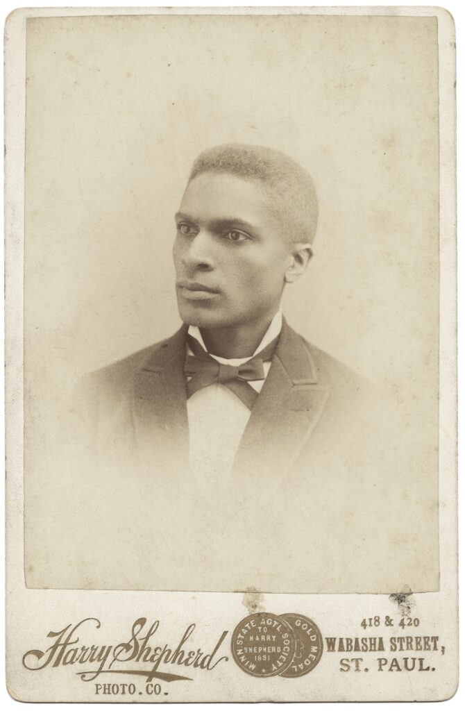 Old faded sepia portrait of a dark skinned man in a suit.