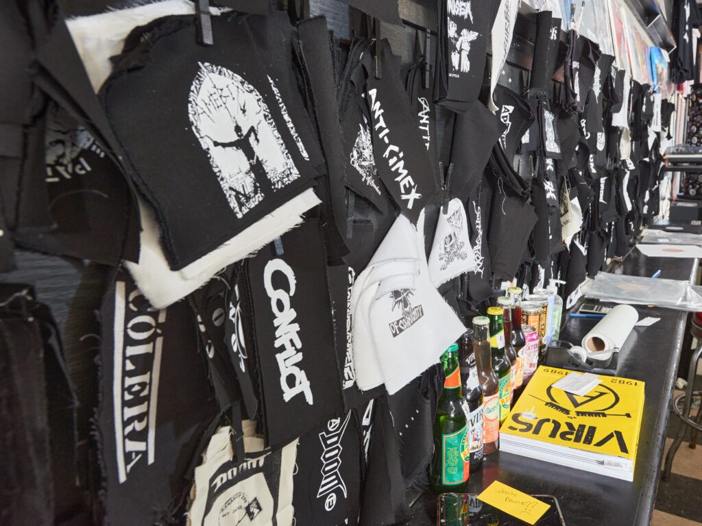Black t-shirts with white designs and writing hung on wall.