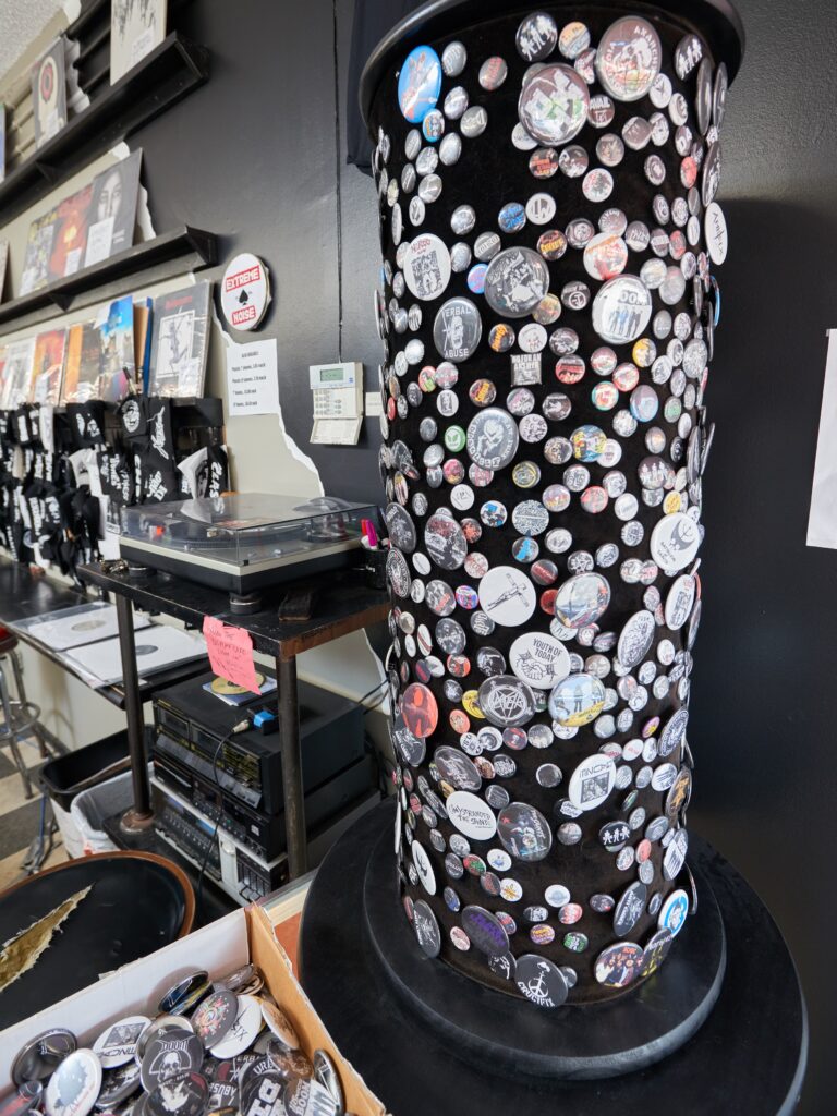 Black column covered with pins, and record player in background.