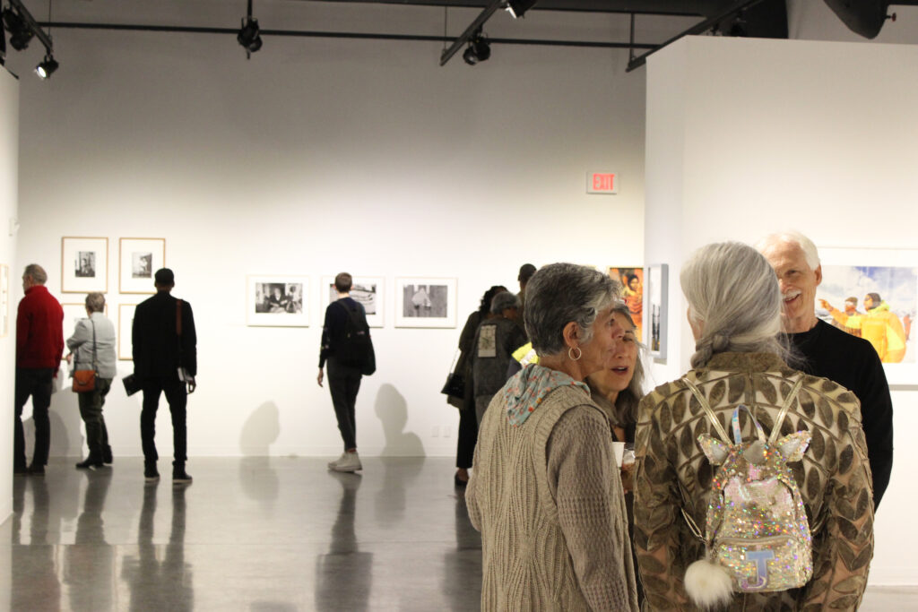 White-walled gallery with photos on walls and people mingling